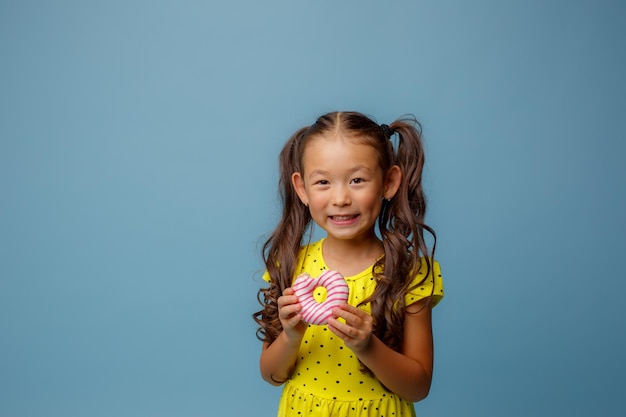 Niña sosteniendo comiendo un donut en un fondo azul