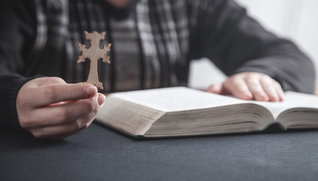 Niña sosteniendo la cruz cristiana y orando sobre la Biblia