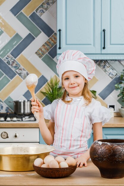 Foto una niña sosteniendo una cuchara de madera para cocinar. el concepto de cocinar en casa.