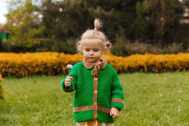 Niña sosteniendo un diente de león en sus manos.