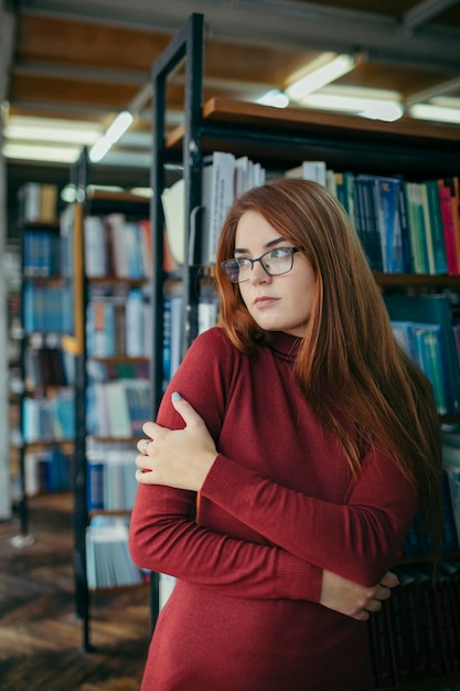 Una niña sosteniendo un estante de libros Foto de alta calidad Estudiante en la biblioteca