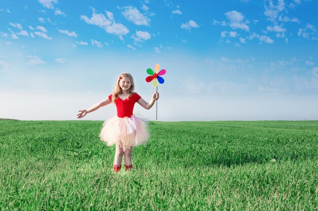 Niña sosteniendo una flor de juguete en el fondo del cielo y el campo