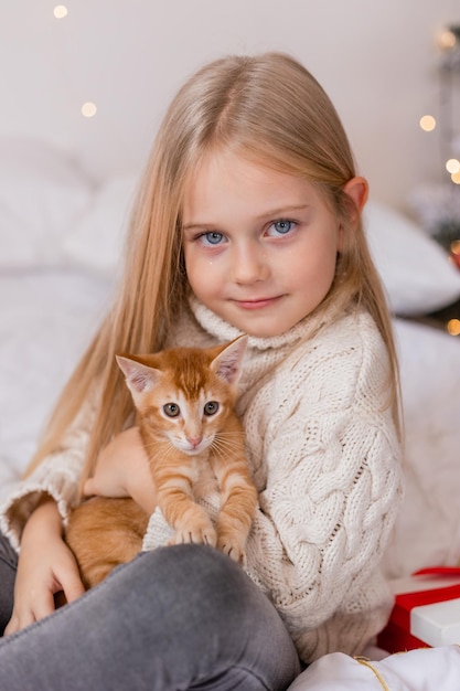 una niña sosteniendo un gato en una cama