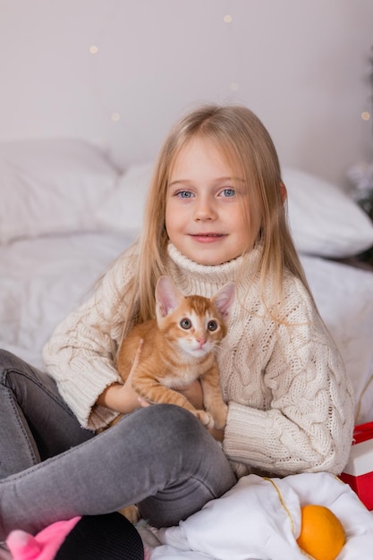 una niña sosteniendo un gato en una cama