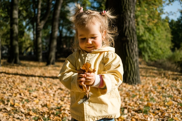 Niña sosteniendo hojas en otoño