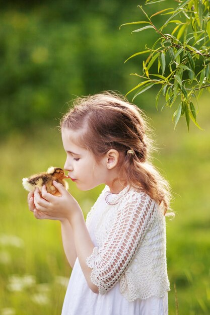 Niña sosteniendo un lindo patito en las manos.