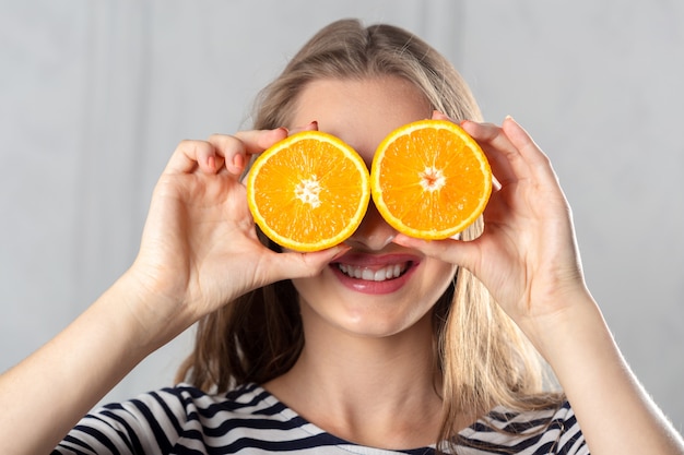 Foto niña sosteniendo naranjas en los ojos