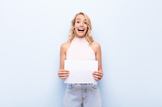 Niña sosteniendo una nota de tablón que parece feliz y gratamente sorprendida