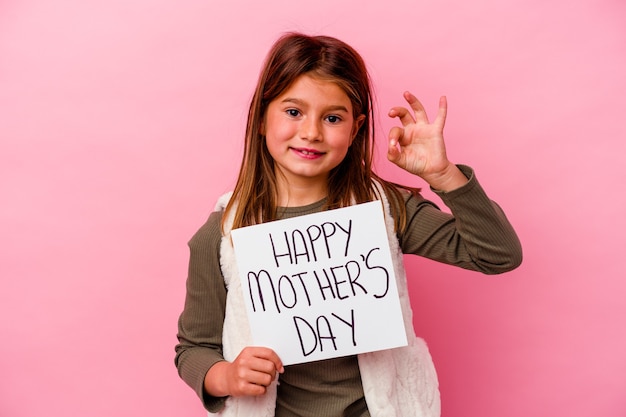 Niña sosteniendo una pancarta del día de las madres felices aislada sobre fondo rosa