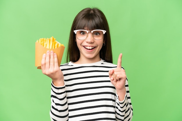 Foto niña sosteniendo papas fritas sobre un fondo de clave de croma aislado que señala una gran idea