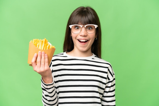 Niña sosteniendo patatas fritas sobre fondo clave de croma aislado