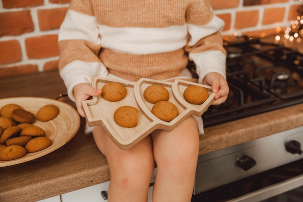 Niña sosteniendo un plato en forma de espina de pescado. hay galletas en el plato.