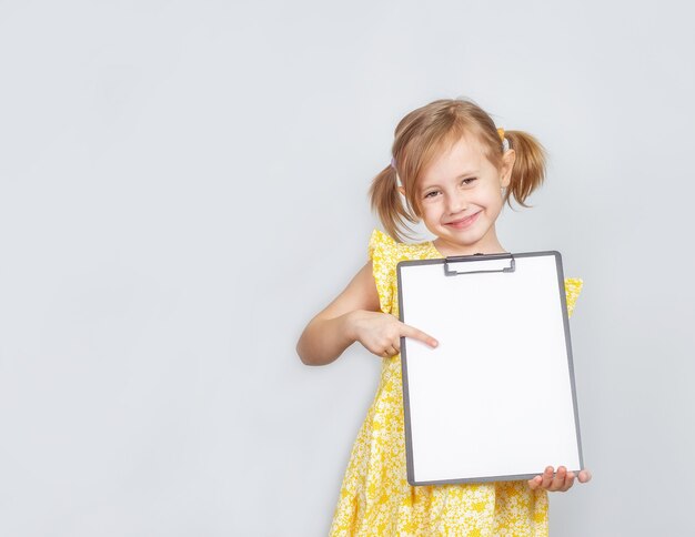 Niña sosteniendo un portapapeles con un papel en blanco