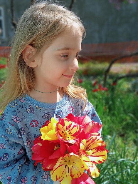 Una niña sosteniendo un ramo de flores.