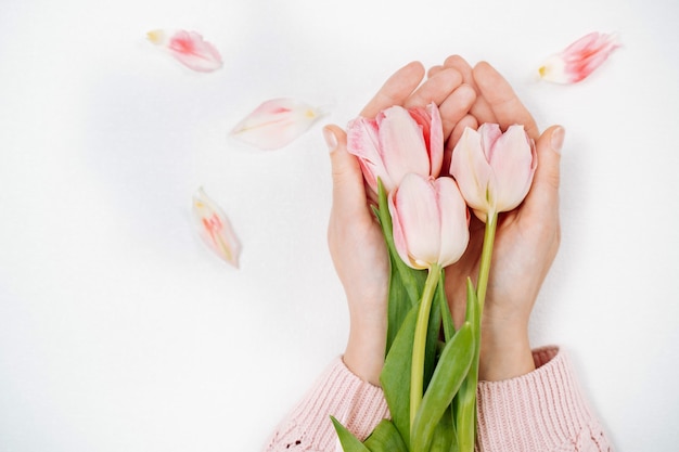 Niña sosteniendo un ramo de tulipanes rosas. Vista superior, fondo blanco, espacio de copia de texto.