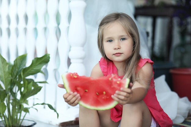 Una niña sosteniendo una rodaja de sandía.