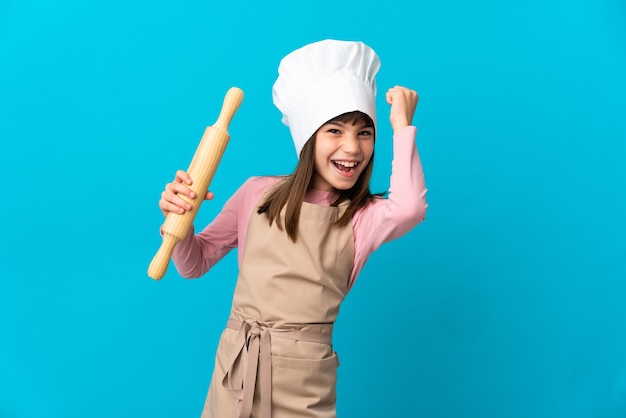 Niña sosteniendo un rodillo aislado sobre fondo azul celebrando una victoria