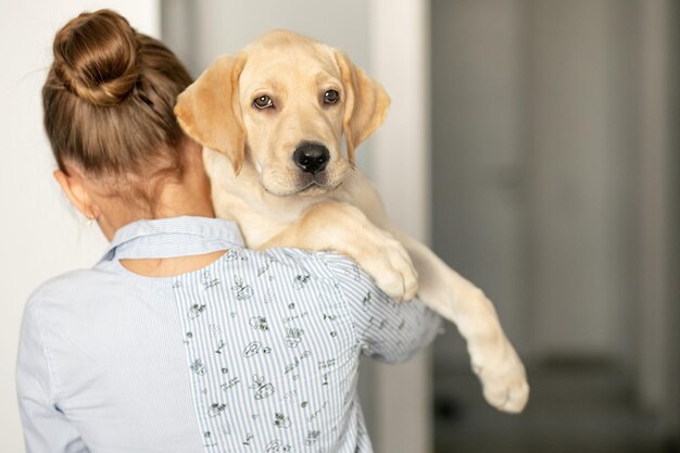 Foto niña sosteniendo a su cachorro labrador en su hombro con un enfoque suave de mirada triste