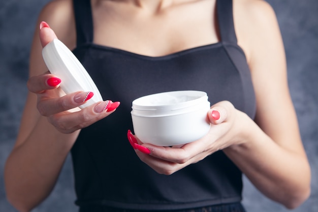 Una niña sosteniendo un tarro de crema en sus manos