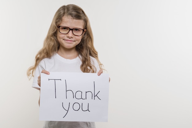 Niña sosteniendo un trozo de papel con la palabra GRACIAS