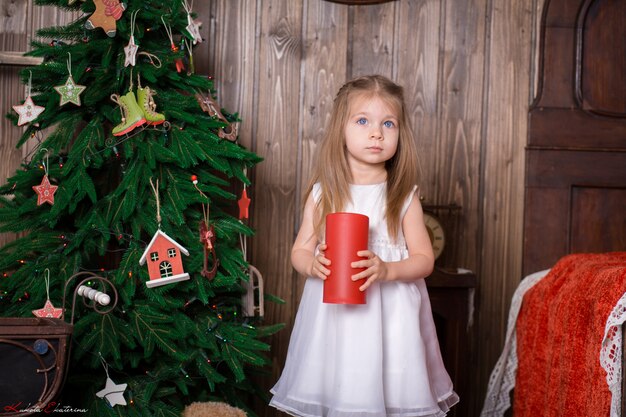 Niña sosteniendo una vela roja decorativa para decorar una habitación para las vacaciones de Navidad