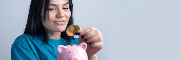 Foto la niña sostiene una alcancía rosa y una moneda en sus manos el concepto de riqueza y acumulación