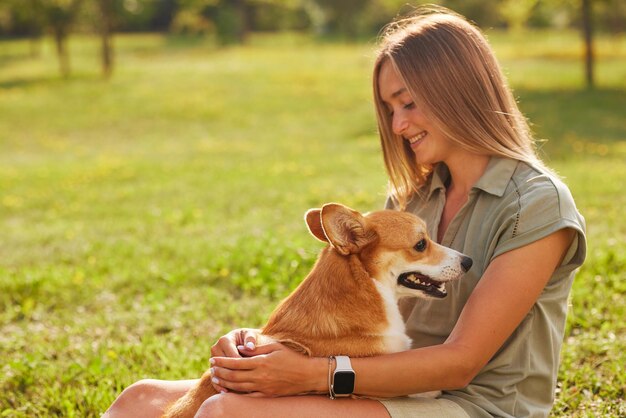 una niña sostiene un alegre y divertido Welsh Corgi en sus brazos en un parque en un clima soleado el concepto de perros felices