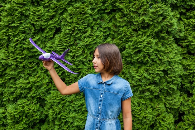 Una niña sostiene un avión de juguete en sus manos.