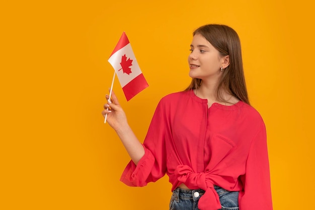 Niña sostiene la bandera de Canadá con fondo naranja brillante Estudiar en Canadá Programa de intercambio de estudiantes