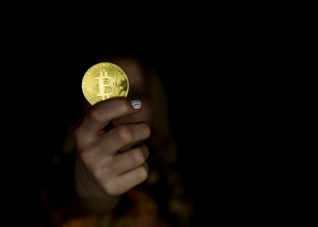 La niña sostiene bitcoin en su mano extendida.