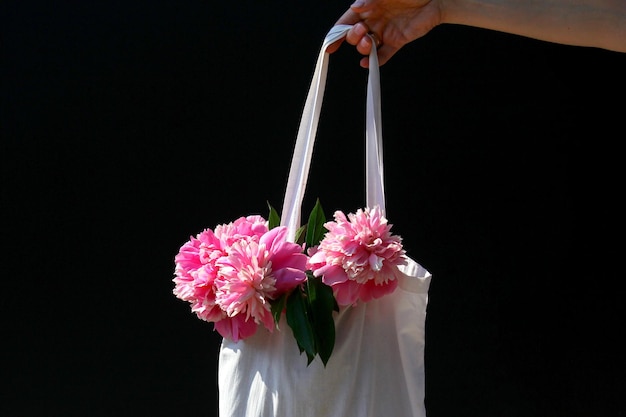 La niña sostiene una bolsa con flores de verano, peonías, estilo de vida de verano.