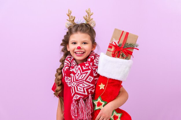 Una niña sostiene una bolsa de regalo de Navidad y sonríe.