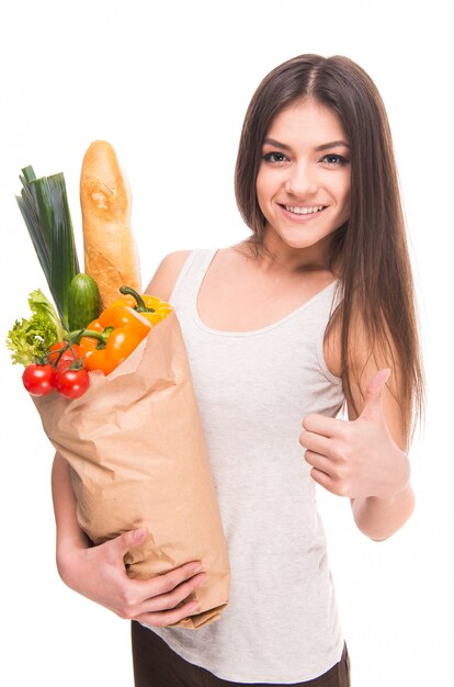 Niña sostiene una bolsa de verduras y sonrisas.