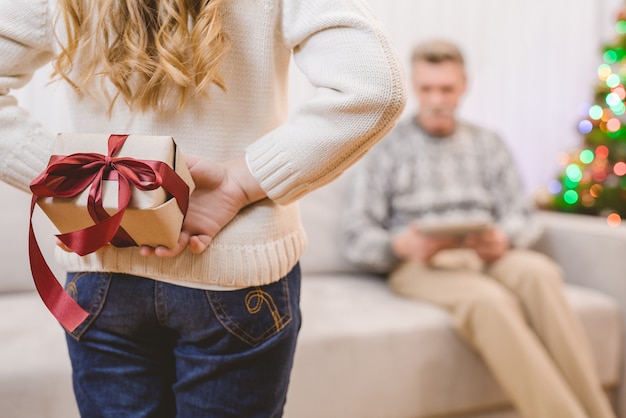 La niña sostiene una caja de regalo para un abuelo.