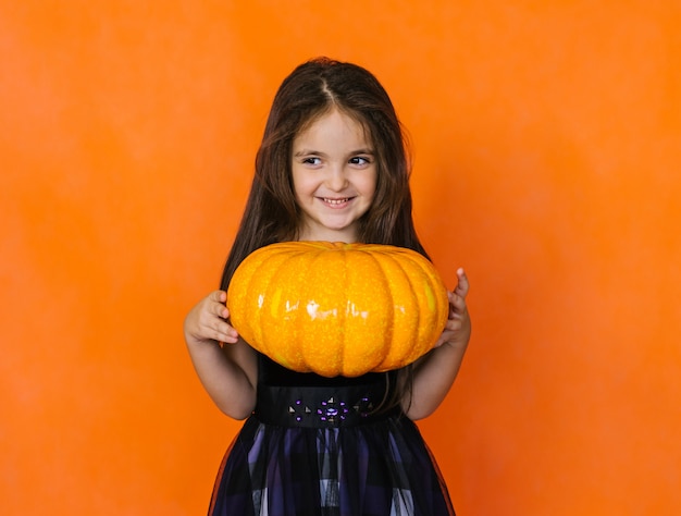 Una niña sostiene una calabaza Decoraciones para la fiesta de Halloween.