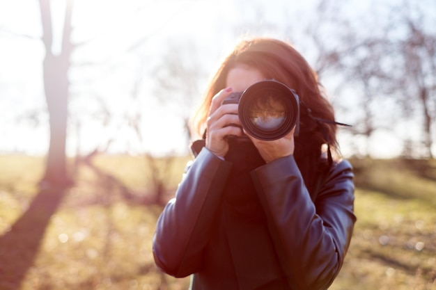La niña sostiene una cámara en sus manos y toma una foto con entusiasmo Camina en la naturaleza en un día soleado