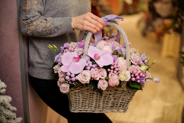 Niña sostiene una canasta de flores de color púrpura, incluyendo rosas y orquídeas