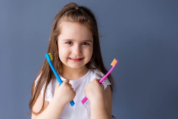 Una niña sostiene un cepillo de dientes en sus manos.