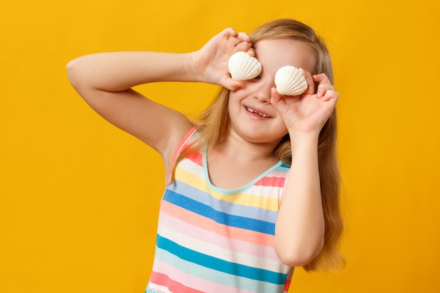 La niña sostiene conchas marinas en lugar de ojos.