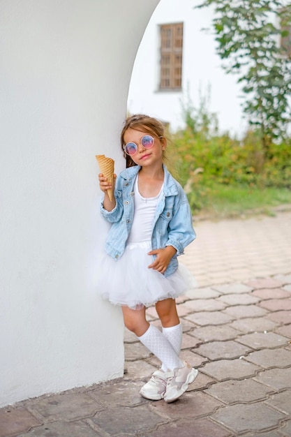 Una niña sostiene un cono de galleta con helado en las manos.