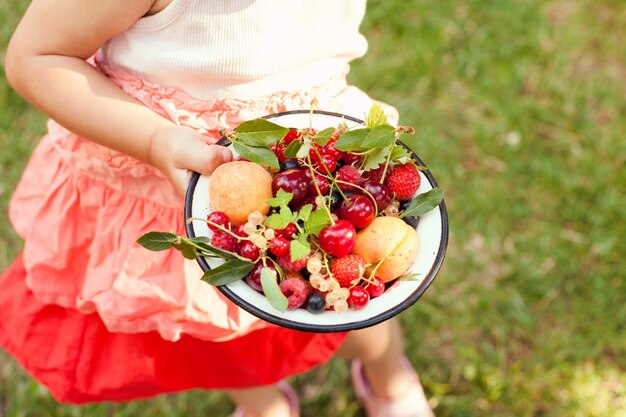 Niña sostiene un cuenco con frutas de verano