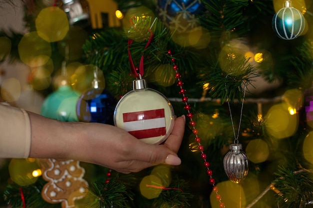 Una niña sostiene una decoración en un árbol de Navidad con la bandera de Austria