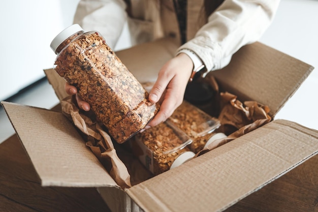 La niña sostiene un frasco de granola en sus manos desempacando los productos.