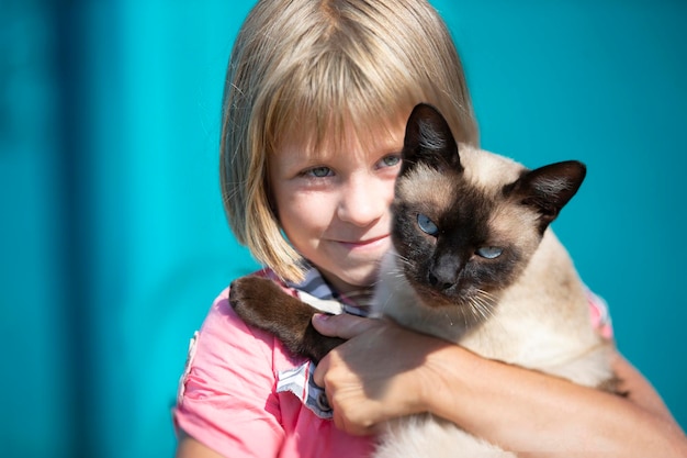 Una niña sostiene un gatito en sus brazos y mira a la cámara.