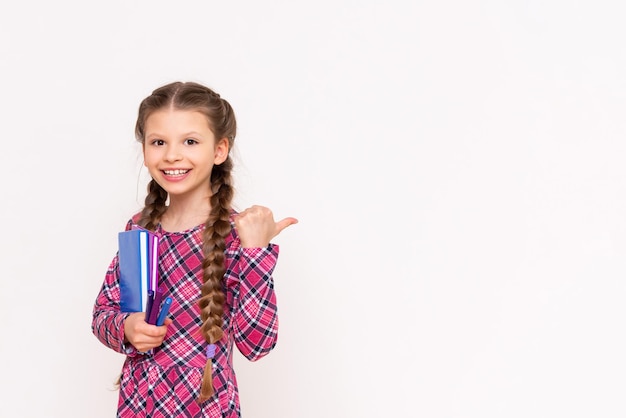 Una niña sostiene un libro y señala su anuncio sobre un fondo blanco aislado Lectura para escolares