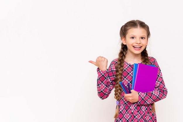 Una niña sostiene un libro y señala su anuncio sobre un fondo blanco aislado Lectura para escolares