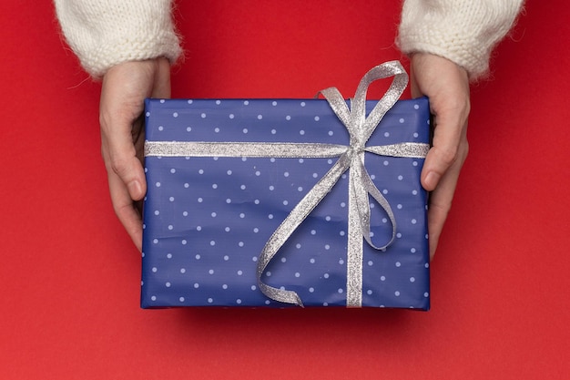 Niña sostiene en las manos cajas de regalo azules en papel con lunares con cinta atada como regalo
