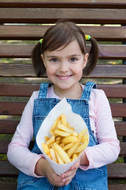 La niña sostiene papas en la mano El niño con una sonrisa mira directamente a la cámara