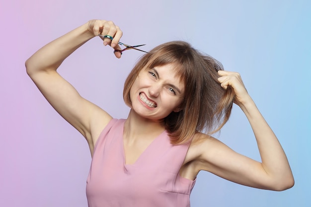 Niña sostiene un par de tijeras en su mano y está a punto de cortarse el pelo