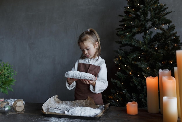 Una niña sostiene un pastel de Navidad con azúcar en polvo en sus manos